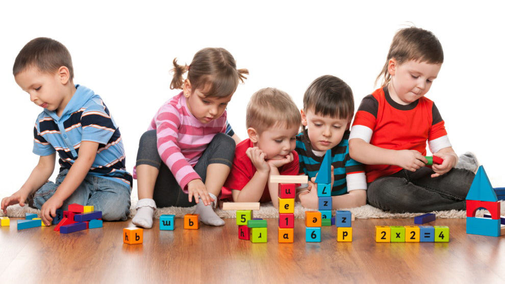 Gruppe von Kindern spielt auf dem Boden mit Würfeln