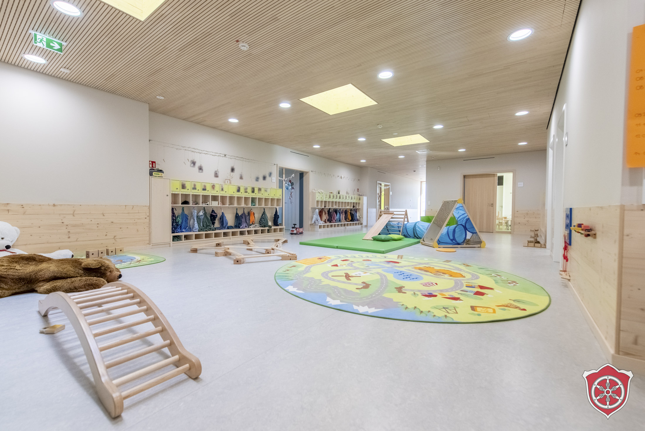 Bewegungsflur mit Kletterdreieck, 2 großen Kuschelteddybören und einer Bewegungslandschaft sind zu sehen.