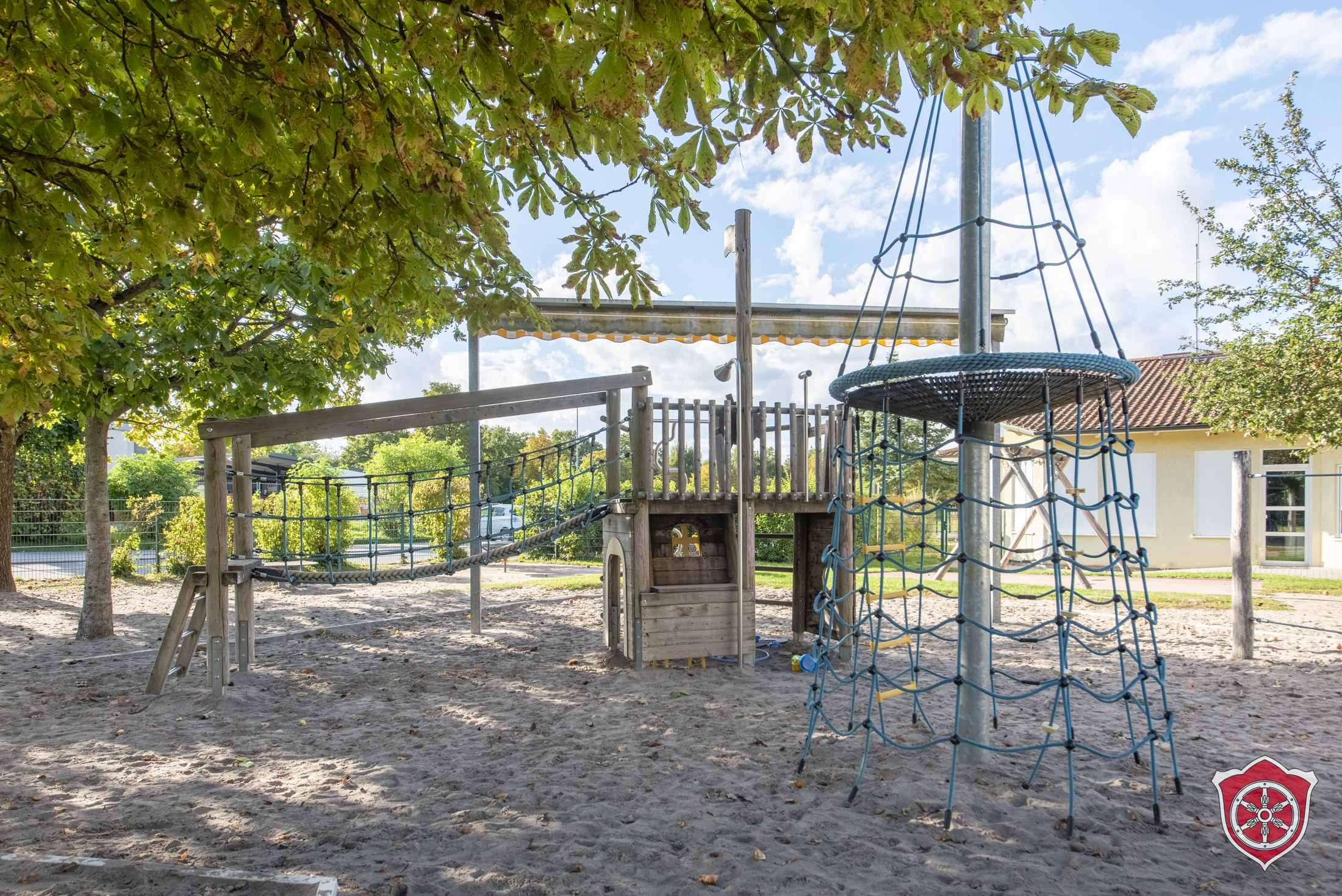 Man sieht eine Sandfläche des AUßenbereichs, Darauf steht ein Klettergerüst.