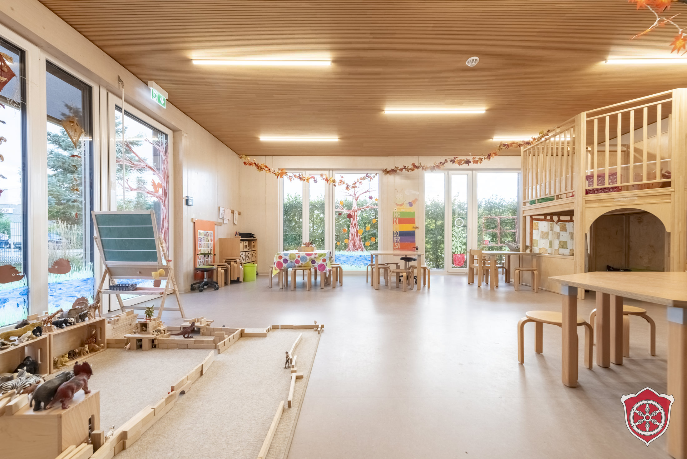 Gruppenraum zeigt Bauklötze und Schleichtiere, mit denen etwas gebaut wurde. Dazu sind mehrer Tischgruppen im Raum und eine Hochebene.